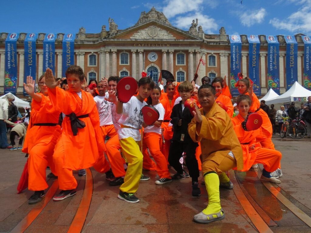 Groupe de pratiquants de kung-fu en démonstration sur la Place du Capitole à Toulouse, exécutant des mouvements synchronisés